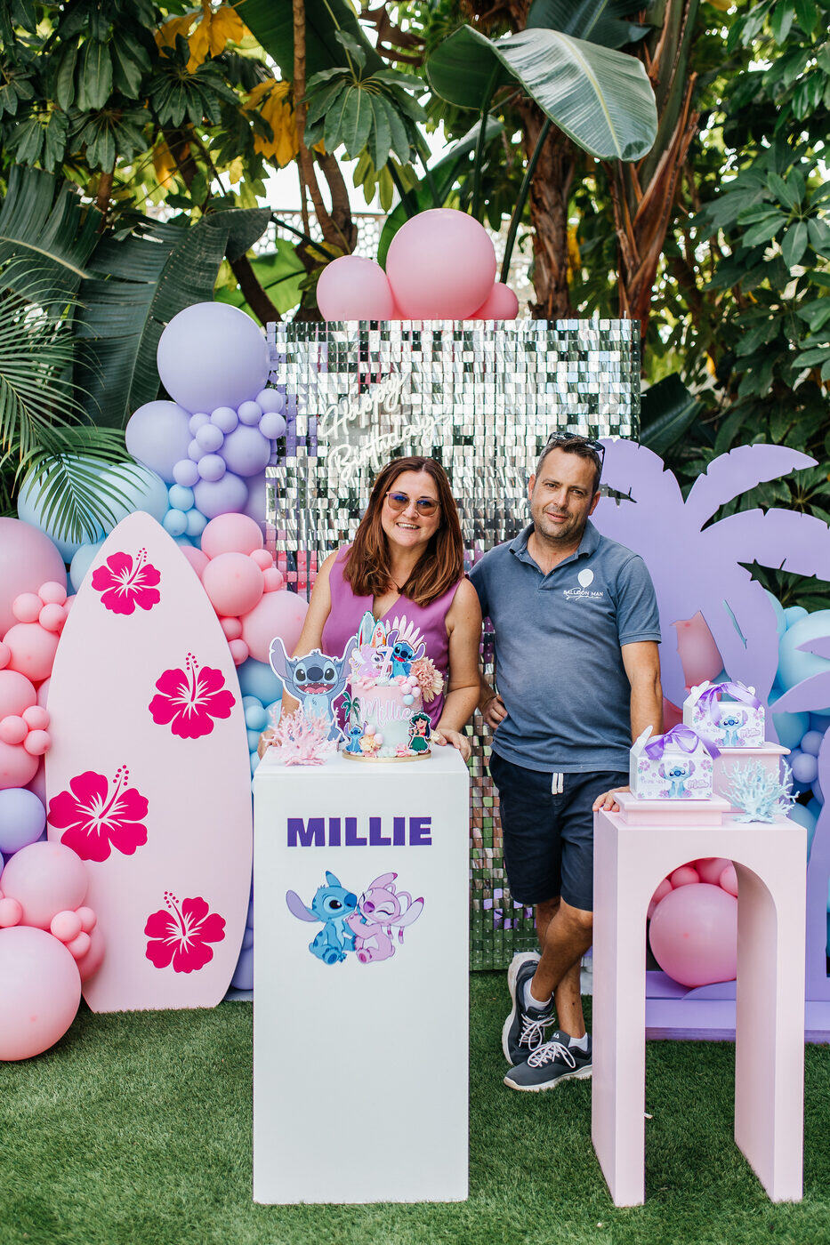 Laura and Cristino of Balloon Man Spain beside a pastel Stitch-themed balloon and sequin backdrop, Marbella