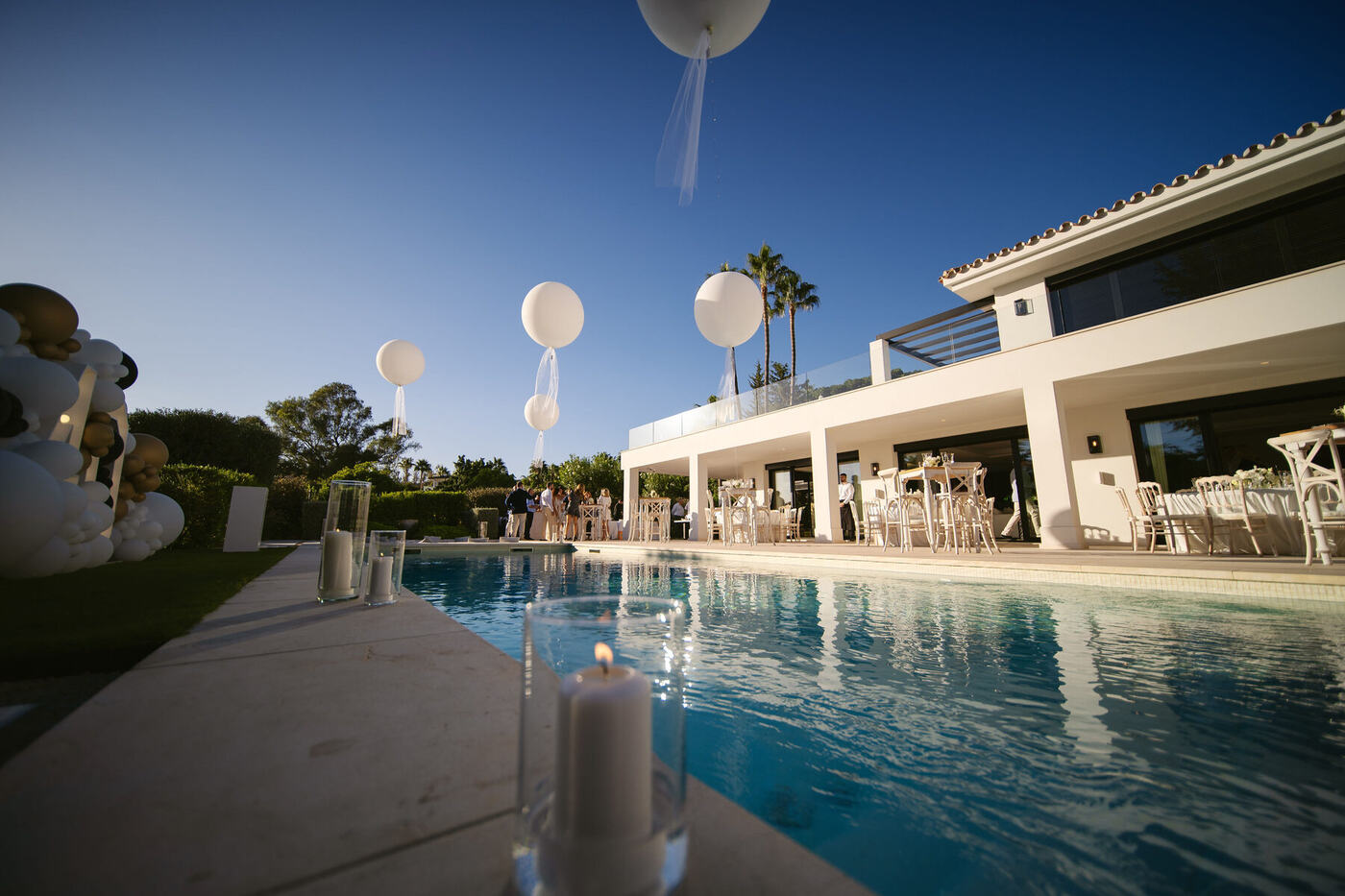 Jumbo round balloons beside a villa pool at dusk, styled table setting, Marbella