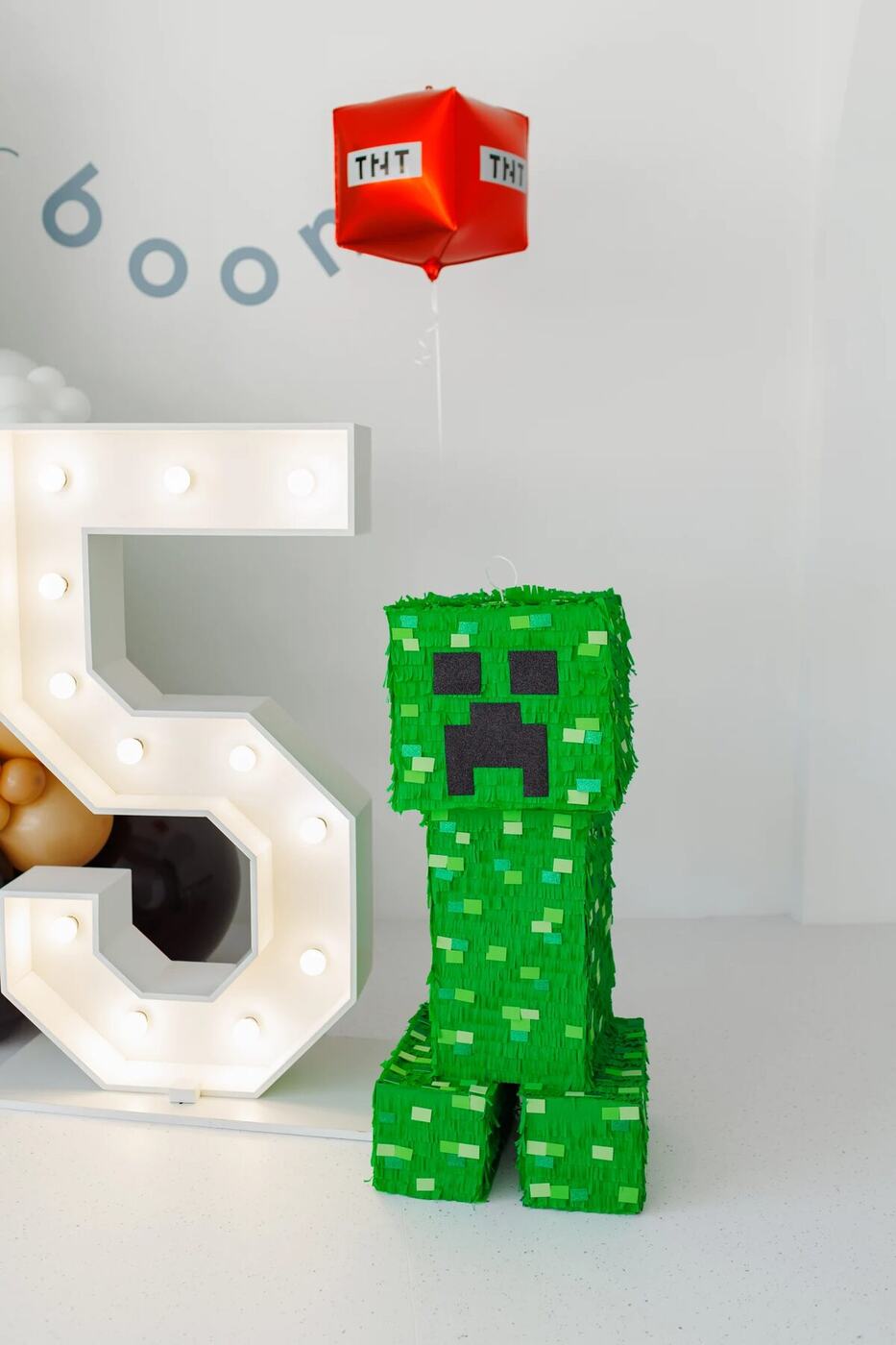 Creeper piñata and red TNT foil balloon beside light-up 5 numbers, Minecraft birthday
