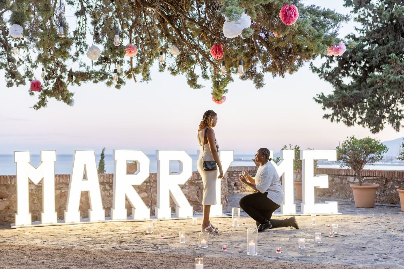MARRY ME light-up letters proposal under fairy-light tree, Marbella coast