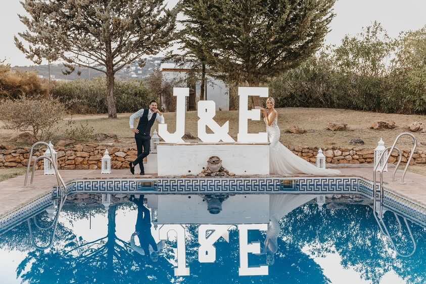 J&E giant marquee letters beside a pool with bride and groom, Marbella wedding